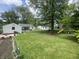 Expansive backyard with green grass, mature trees, and a playset at 828 N Clarkdale Dr, Muncie, IN 47304