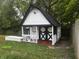 Backyard playhouse featuring a charming design, black and white trim, and a small porch at 8445 Montery Rd, Indianapolis, IN 46226