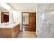 Bathroom featuring a shower, double sinks, wooden cabinets, and updated lighting at 8619 Wrangler Ct, Indianapolis, IN 46217