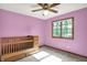 Bedroom with lavender walls, a crib, and a bright window at 8619 Wrangler Ct, Indianapolis, IN 46217