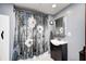 Clean bathroom features a vanity with sink, shower with floral curtain, and modern fixtures at 8879 W County Road 700 S, Coatesville, IN 46121