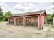 Three-car garage featuring wooden doors and red trim, with a well-maintained driveway at 8879 W County Road 700 S, Coatesville, IN 46121