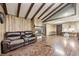 Spacious living room with wood paneling, exposed beam ceiling, fireplace, and a comfortable brown leather sofa at 8879 W County Road 700 S, Coatesville, IN 46121