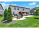 Expansive backyard with concrete patio, outdoor furniture, fire pit, lush lawn, and well-maintained landscaping at 9716 Cimmaron Ave, McCordsville, IN 46055