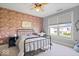 This bedroom has a brick accent wall, a ceiling fan and large windows offering a view of the backyard at 10054 Win Star Way, Fishers, IN 46040