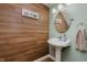Charming powder room features wood accent wall, pedestal sink, decorative mirror and soft, neutral colors at 102 Roxbury Ln, Noblesville, IN 46062
