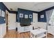 Spacious living room features blue walls, white trim, hardwood floors, and a large television at 102 Roxbury Ln, Noblesville, IN 46062