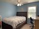 A cozy bedroom with light blue walls, ceiling fan, and a large window providing natural light at 10760 Independence Way, Carmel, IN 46032