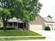Charming brick home featuring a two-car garage, well-manicured lawn, and mature landscaping at 10760 Independence Way, Carmel, IN 46032