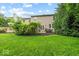 A spacious backyard with lush green grass, mature trees, and a patio area featuring outdoor seating at 11987 Quarry Ct, Fishers, IN 46037