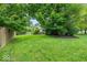 Lush backyard featuring a sprawling green lawn, mature trees, and partially fenced perimeter at 11987 Quarry Ct, Fishers, IN 46037