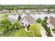 Aerial view of a brick home surrounded by trees with a manicured lawn and waterfront access at 12192 Woods Bay Pl, Carmel, IN 46033