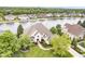 Aerial view of a brick home surrounded by trees with a manicured lawn and waterfront access at 12192 Woods Bay Pl, Carmel, IN 46033