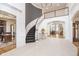Elegant foyer with curved staircase, custom millwork, and stone floors offers a warm welcome into the home at 12192 Woods Bay Pl, Carmel, IN 46033