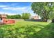 Expansive back yard has a lush green lawn, mature trees, and a red deck with built-in benches at 13172 E 116Th St, Fishers, IN 46037