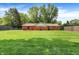 Large, grassy back yard featuring a red brick home, mature trees, and a wooden privacy fence at 13172 E 116Th St, Fishers, IN 46037