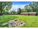 Wide back yard has a large grassy area with mature trees, a fire pit, and a red brick home at 13172 E 116Th St, Fishers, IN 46037