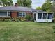 A quaint brick home featuring a sunroom addition and attractive foundation landscaping at 1322 Greenway Dr, Anderson, IN 46011