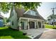 Three-car garage with stone pillars, dark wooden doors, and hanging ferns, attached to green home at 140 4Th Nw St, Carmel, IN 46032