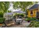 Inviting backyard patio with mature landscaping, patio umbrellas, seating, and greenhouse at 224 N Pennsylvania St, Greenfield, IN 46140
