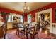 Elegant red dining room with a glass top table, stylish chandelier, and adjacent living room at 224 N Pennsylvania St, Greenfield, IN 46140