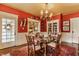 Red dining room with a glass dining table, chandelier, and view into the living room at 224 N Pennsylvania St, Greenfield, IN 46140