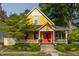 Charming yellow two-story home featuring a welcoming front porch, colorful red door and well-maintained landscaping at 224 N Pennsylvania St, Greenfield, IN 46140