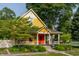 Charming yellow two-story home featuring a welcoming front porch, colorful red door and well-maintained landscaping at 224 N Pennsylvania St, Greenfield, IN 46140
