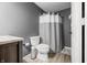 Well-lit bathroom with a toilet, cabinet, and a shower with gray and white shower curtain at 2805 Fox E Ct, Martinsville, IN 46151