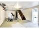 Unfinished basement with exercise equipment, concrete floor, and access to wooden staircase at 3940 E 57Th St, Indianapolis, IN 46220
