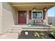 Inviting front porch with seating, charming decor, and pleasant curb appeal with colorful plants and flowers at 4605 Clairmont Dr, Columbus, IN 47203