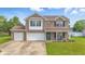 Charming two-story brick home with a well-manicured lawn, a three-car garage, and a welcoming front porch at 5030 E 800 N, Columbus, IN 47203