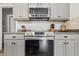 Kitchen features stainless steel microwave and oven, gray cabinets, granite countertops and tiled backsplash at 5030 E 800 N, Columbus, IN 47203