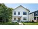 A two-story white home with black trim, a manicured lawn, and lush trees at 615 Orange St, Indianapolis, IN 46203