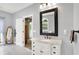 Bright bathroom with marble countertops, white cabinets, and large framed mirror at 7074 E Pine Needle Ln, Morgantown, IN 46160