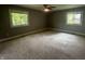 Spacious bedroom featuring neutral carpeting, two windows for natural light, and a ceiling fan at 723 Bennett Rd, Carmel, IN 46032