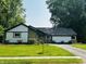 Charming home featuring a well-maintained lawn, contrasted by dark trim against light siding and stone accents at 723 Bennett Rd, Carmel, IN 46032