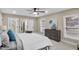 Well-lit bedroom with neutral carpet, a gray headboard, ceiling fan, and natural light from the windows at 7999 Englewood Rd, Indianapolis, IN 46240