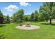 Lush backyard featuring a fire pit with gravel surround, Adirondack chairs, and mature trees at 8510 N Carroll Rd, Indianapolis, IN 46236