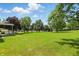 Spacious backyard featuring a lush green lawn and mature trees, offering privacy and shade at 8510 N Carroll Rd, Indianapolis, IN 46236