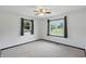 An empty room features carpet, a fan, and two windows providing plenty of natural light at 8510 N Carroll Rd, Indianapolis, IN 46236