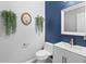Contemporary powder room features vanity with brushed gold hardware, wall decor, and a white toilet at 9709 Prairie Smoke Dr, Noblesville, IN 46060