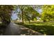 Scenic driveway leading to a property with lush green lawn, mature trees, and a barn in the background at 11823 E 200 S, Zionsville, IN 46077