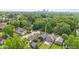A neighborhood aerial view of many houses with a distant cityscape, surrounded by lush green trees on a sunny day at 1205 N Temple Ave, Indianapolis, IN 46201