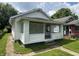 Cozy home featuring a covered front porch and mature trees in the surrounding yard at 1445 W 34Th St, Indianapolis, IN 46208