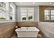 The bathroom features a standalone tub under a window, with wood-look tile floors at 14458 Smickle Ln, Carmel, IN 46033
