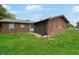 An exterior view of a single-story brick home and overgrown front lawn under a blue sky at 2074 W 300 S, Shelbyville, IN 46176