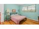 Cozy bedroom boasts wood floors, aqua walls, a floral comforter, and natural light from the windows at 2233 Washington St, Columbus, IN 47201