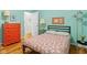 Bright bedroom with wood floors, floral comforter, orange dresser, and a view into the hallway at 2233 Washington St, Columbus, IN 47201