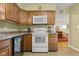 Efficient kitchen with wooden cabinets, a white oven, and dishwasher, connected to the bright living room at 2233 Washington St, Columbus, IN 47201